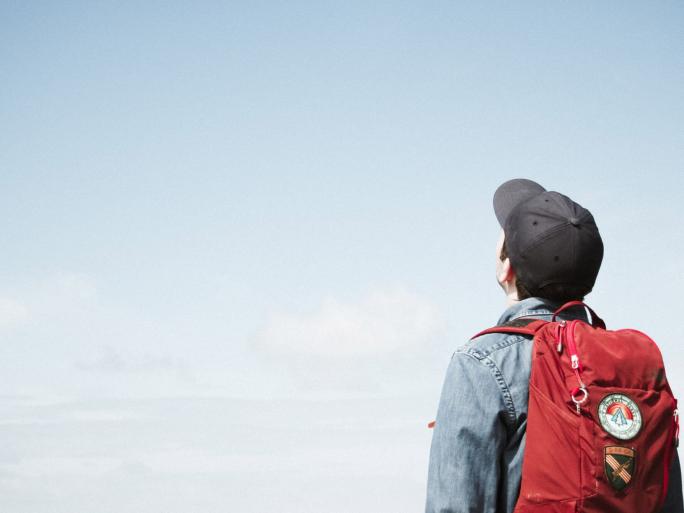 Mann mit Rucksack schaut in den Himmel